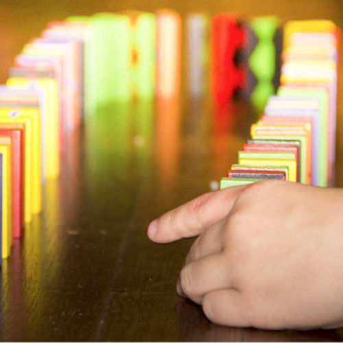 Eine Kinderhand setzt Dominosteine. Die Systemische Therapie in der Praxis Christina Pielken stößt Veränderung an wie ein Domino.