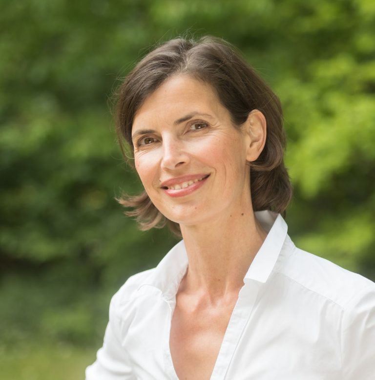 Therapeutin Christina Pielken lächelnd vor Wald und Bäumen