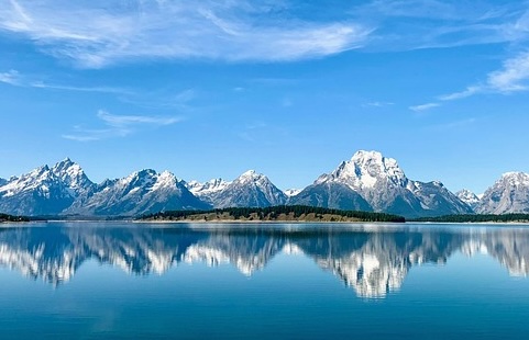Schnee auf Bergspitzen vor Bergsee