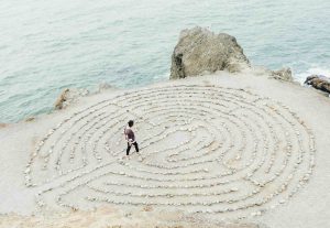 Steinkreis am Meer, Frau übt Gehmeditation als Achtsamkeitsübung und Gehmeditation